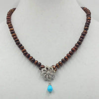 Get your sunglasses. This amazing necklace is blinding.  14KWG, bronze pearl necklace with 14KWG .72ct diamond & turquoise pendant on hand-knotted purple silk. 19.50" Length.