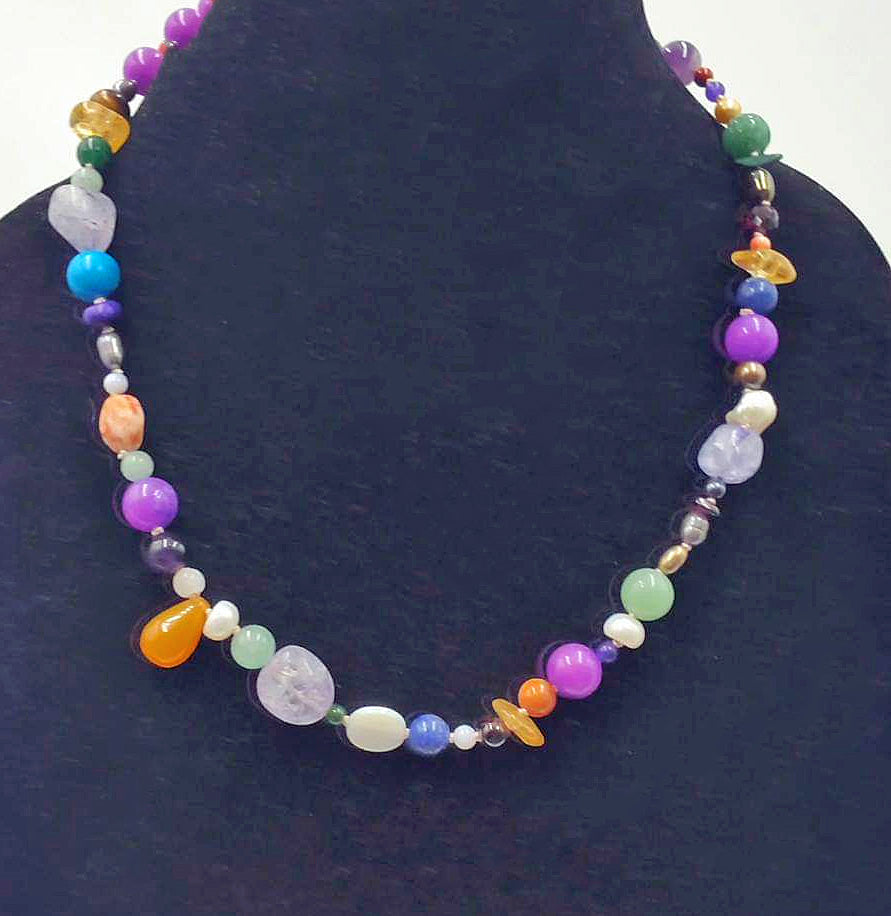 Multi-stone cosmic necklace with sterling silver clasp on white silk.
