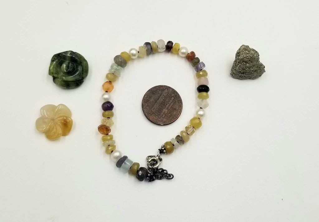 Adjustable sterling silver and multi-stone bracelet on purple silk. 6.75" - 8.25" length.