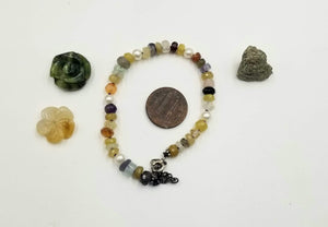 Adjustable sterling silver and multi-stone bracelet on purple silk. 6.75" - 8.25" length.
